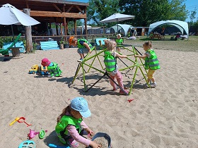 Dzieci bawią się na placu zabaw w piasku i wchodzą na drabinki