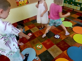 Dzieci segregują kartoniki z owocami według koloru, do odpowiedniego kółka. 