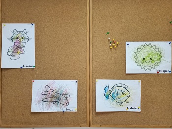 Na korkowej tablicy wiszą 4 pokolorowane przez dzieci obrazki, które przedstawiają ich znaczki. Jaśmina -kot, Jerzy -samolot, Gabriela -ryba, Stsiapan - słońce.