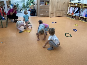 Na podłodze leżą szarfy, dzieci poruszają się na czworaka po podłodze.