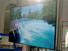 Na ekranie telewizora widać dzieci, które znajdują się przy wodospadzie.