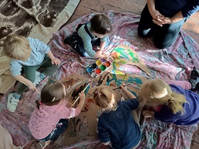 Dzieci malują farbami dużego konia na podłodze