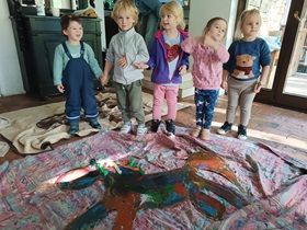 Dzieci stoją przy pomalowanym koniu i prezentują swoją wspólną pracę