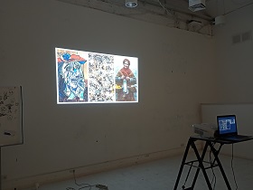 Na białej ścianie wyświetlony jest slajd, który przedstawia trzy obrazy. 