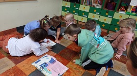 Dzieci przyglądają się graficznemu znakowi litery Y i palcem rysują po jej śladzie. 
