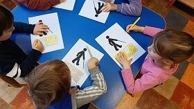 Dzieci przy stoliku kolorują na żółto obrazek pasów dla niewidomych.
