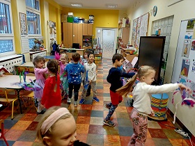 Dzieci chodzą po sali i ruszają swoimi plastikowymi kubkami z kolorową bibułą. 
