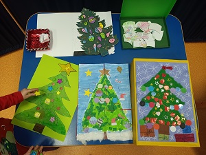 Na niebieskim stoliku leżą prace konkursowe wykonane przez dzieci. Są to puzzle o tematyce świątecznej.
