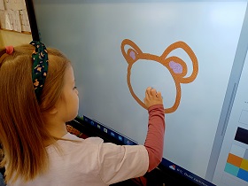 Dziewczynka w opasce rysuje głowę tygrysa na monitorze w aplikacji Paint.