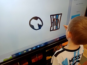 Chłopiec rysuje piłkę nożną i koszulkę z numerem 10 na monitorze w aplikacji Paint.