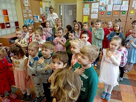 Dzieci stoją w grupie w sali. Mają ułożoną rękę na sercu w celu złożenia przysięgi.