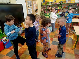 Dzieci stoją w parach z założonymi rękami i twarzami do siebie. 