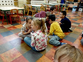 Dzieci siedzą w parach twarzami do siebie. 
