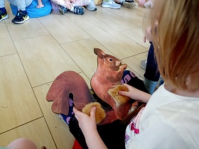 Dziewczynka dotyka figurki wiewiórki, na którym jest przyklejony kawałek materiału. 
