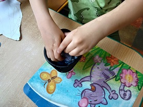 Chłopiec rączkami miesza masę z papieru i wody. 