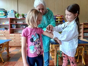 Pani Hania w raz z dwoma dziewczynkami odgrywają scenkę szczepienia. 