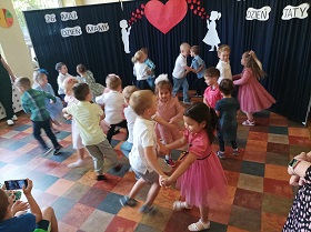 Dzieci trzymają się za dłonie i tańczą w parach.
