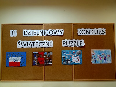 Na tablicy korkowej wisi napis II dzielnicowy konkurs świąteczne puzzle oraz cztery prace plastyczne w formacie A3.