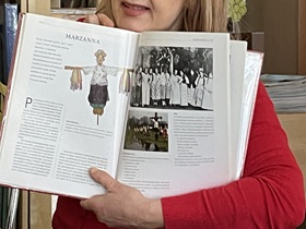 Pani w czerwonej bluzce trzyma otwartą książkę ze zdjęciem Marzanny.