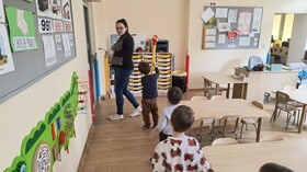 Dzieci i nauczycielka wychodzą z sali. Pierwsze dziecko- chłopiec trzyma w ręku papierowy znicz olimpijski.