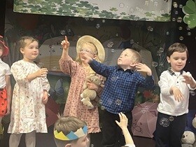 Czwórka dzieci stoi na scenie, wokół nich są bańki mydlane.