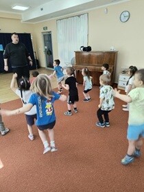 Dzieci skierowane są twarzą do prowadzącego i skaczą obunóż.