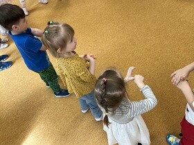 Na dywanie stoją dzieci i wykonują ruchy mycia dłoni.