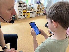 Chłopiec trzyma w dłoniach telefon z odblokowaną klawiaturą.