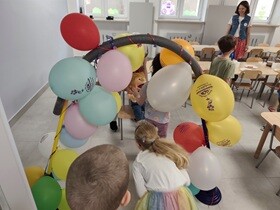Dzieci wchodzą do sali przechodząc przez tunel z kolorowych balonów.